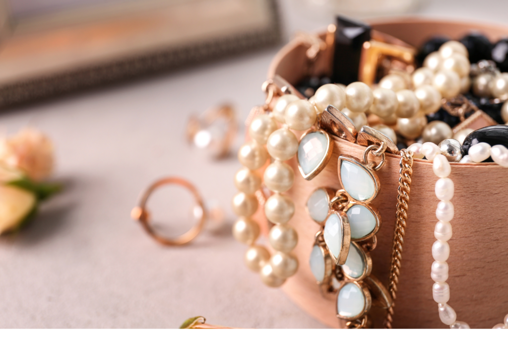 Eine Schmuckschatulle mit goldenen und perlenbesetzten Schmuckstücken, darunter Halsketten, Armbänder und Ringe.